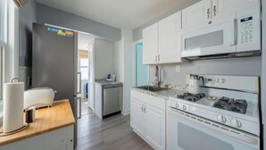 Una cocina moderna con gabinetes blancos, un microondas, una estufa y un tostador.