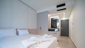 Une chambre d’hôtel avec un grand lit, une armoire, une salle de bain avec un miroir et une porte donnant sur une autre pièce.