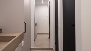 Un couloir moderne avec un plancher de couleur claire, un comptoir en bois sur la gauche et des portes noires sur la droite.