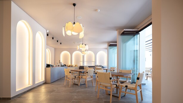 Un intérieur moderne avec un comptoir d’accueil, des chaises en bois et des luminaires suspendus.