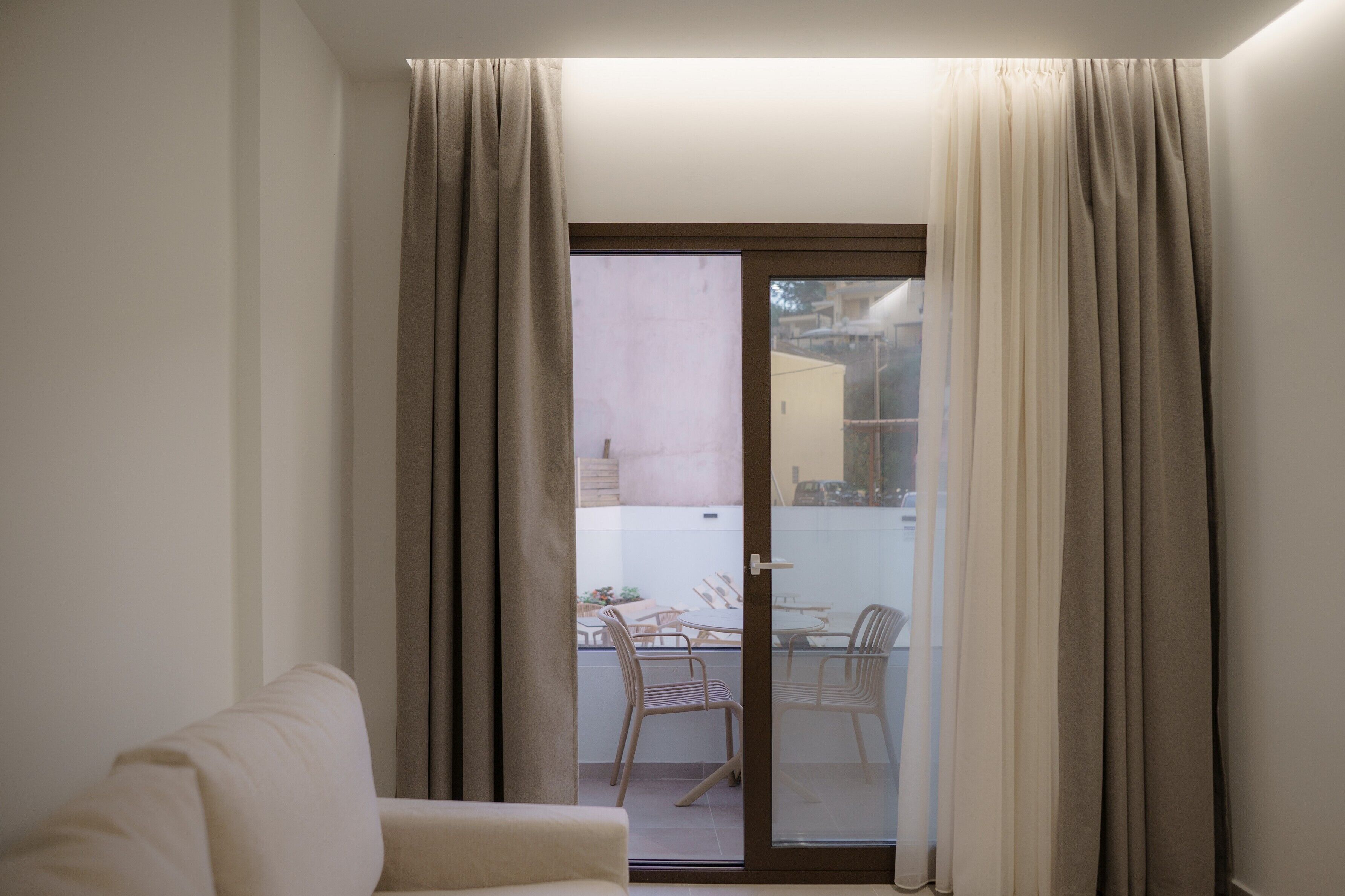 Ein Zimmer mit einer Schiebetür, die zu einem Außenbereich mit Tisch und Stühlen führt.