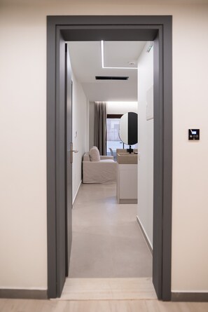 Habitación de hotel moderna con diseño minimalista, que incluye un sofá, una mesita de noche y un espejo grande.