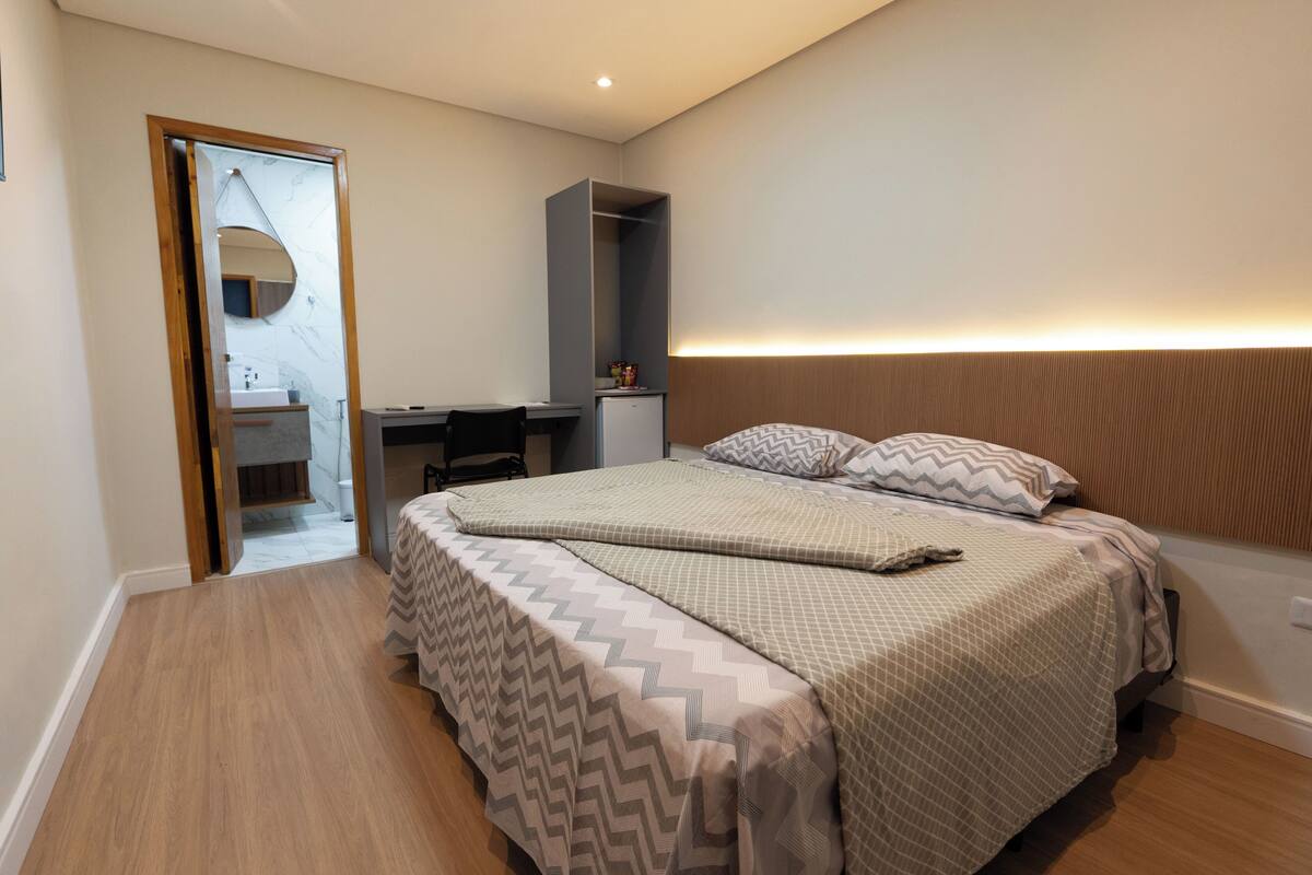 Quarto com cama, mesa de cabeceira e guarda-roupa.