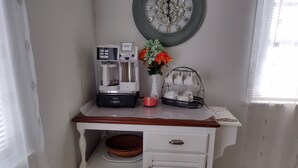 Una kitchenette con una cafetera, un florero con flores y un juego de té sobre una bandeja.