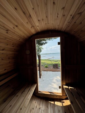 A wooden cabin with a door leading to a view of a lake and dock.