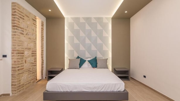 Un dormitorio moderno con cama, mesitas de noche y un muro con estampado geométrico.