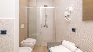Un baño moderno con ducha de vidrio, inodoro y tocador con una toalla.