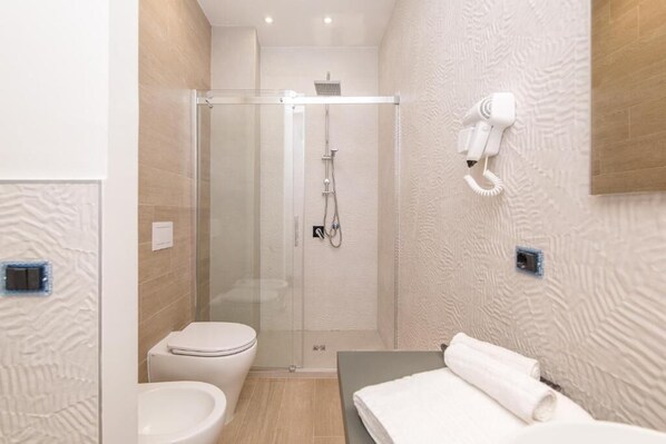 A modern bathroom with a glass-enclosed shower, a toilet, and a vanity with a towel. - Le note di Fred (Campobasso)