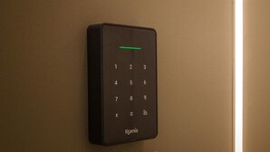 Un panel de control Ksenia fijado a la pared con una luz indicadora verde.