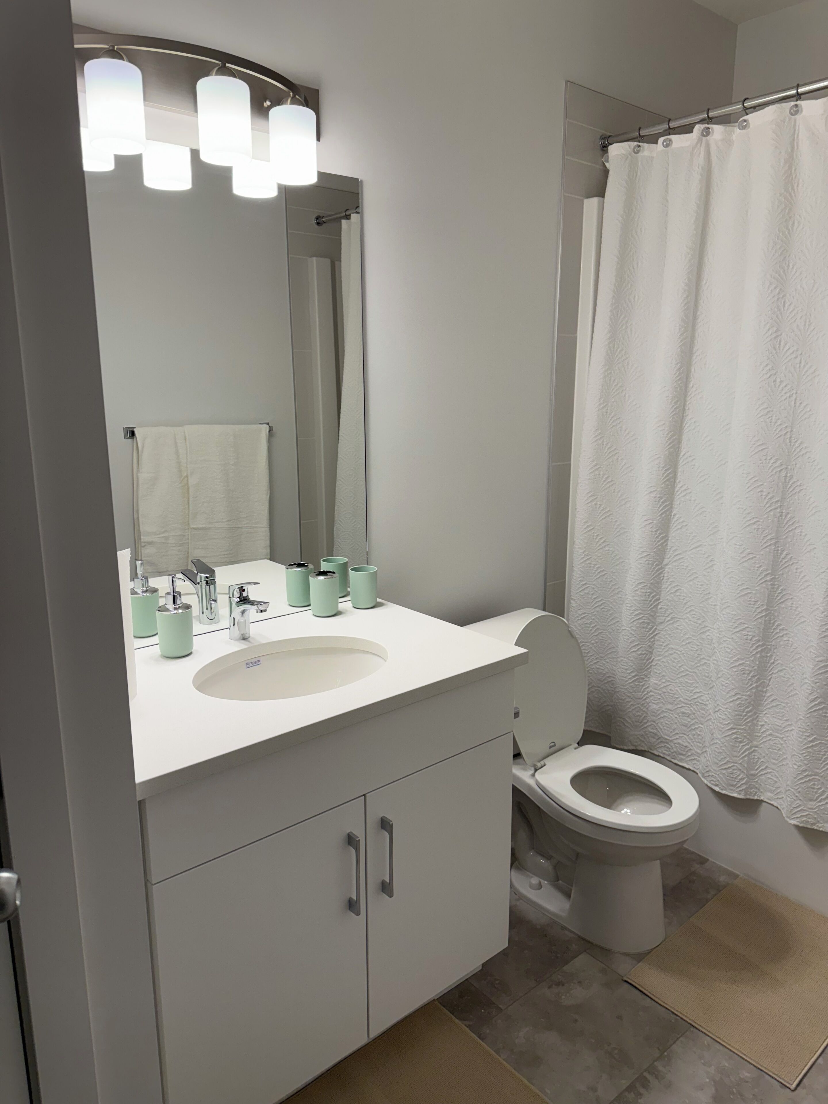 A modern bathroom with a white sink, a toilet, and a shower curtain.
