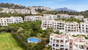 Un quartier résidentiel composé d’immeubles à plusieurs étages, doté d’une piscine et bordé de collines.