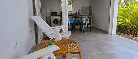 Un espace extérieur propre et moderne, avec une table et des chaises, un lave-linge et une cuisine en arrière-plan.