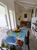 Un comedor con una mesa preparada para dos personas, un frutero y vistas de la cocina y la sala de estar.