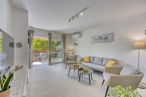 A modern living room with a sofa, two armchairs, a coffee table, and a dining area visible through glass doors. - Family Apartment - Cosy & Modern, 850 meters to the Sea (Porec)