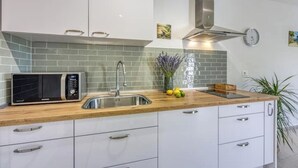 A modern kitchen with white cabinets, a stainless steel sink, a microwave, and a wooden countertop. - Family Apartment - Cosy & Modern, 850 meters to the Sea (Porec)