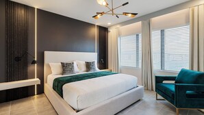 Un dormitorio moderno con una cama grande, ventilador de techo y vistas al exterior a través de las ventanas.