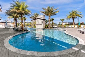 Ein Pool mit Palmen, Liegestühlen und einem Steinhaus.