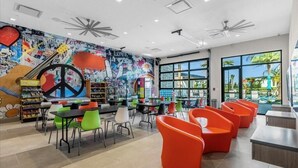 Un área de juegos infantil vibrante, con asientos coloridos y un mural con símbolos de paz e instrumentos musicales.