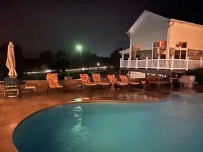 Ein Schwimmbecken mit Liegestühlen und einem Gebäude im Hintergrund.