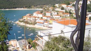 Eine Küstenstadt mit Gebäuden entlang der Uferlinie, Blick auf das klare Meer und einem bergigen Hintergrund.