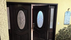 A double door with decorative glass panels, a potted plant, and a tiled entrance area. - Chic 1-bedroom apartment with ocean views, sun bathing deck, pool in Ensenada. (Ensenada)