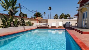 A swimming pool with two lounge chairs and a covered area. - Chic 1-bedroom apartment with ocean views, sun bathing deck, pool in Ensenada. (Ensenada)