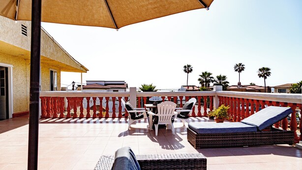 An outdoor patio with a table and chairs, a sofa, and a potted plant. - Chic 1-bedroom apartment with ocean views, sun bathing deck, pool in Ensenada. (Ensenada)