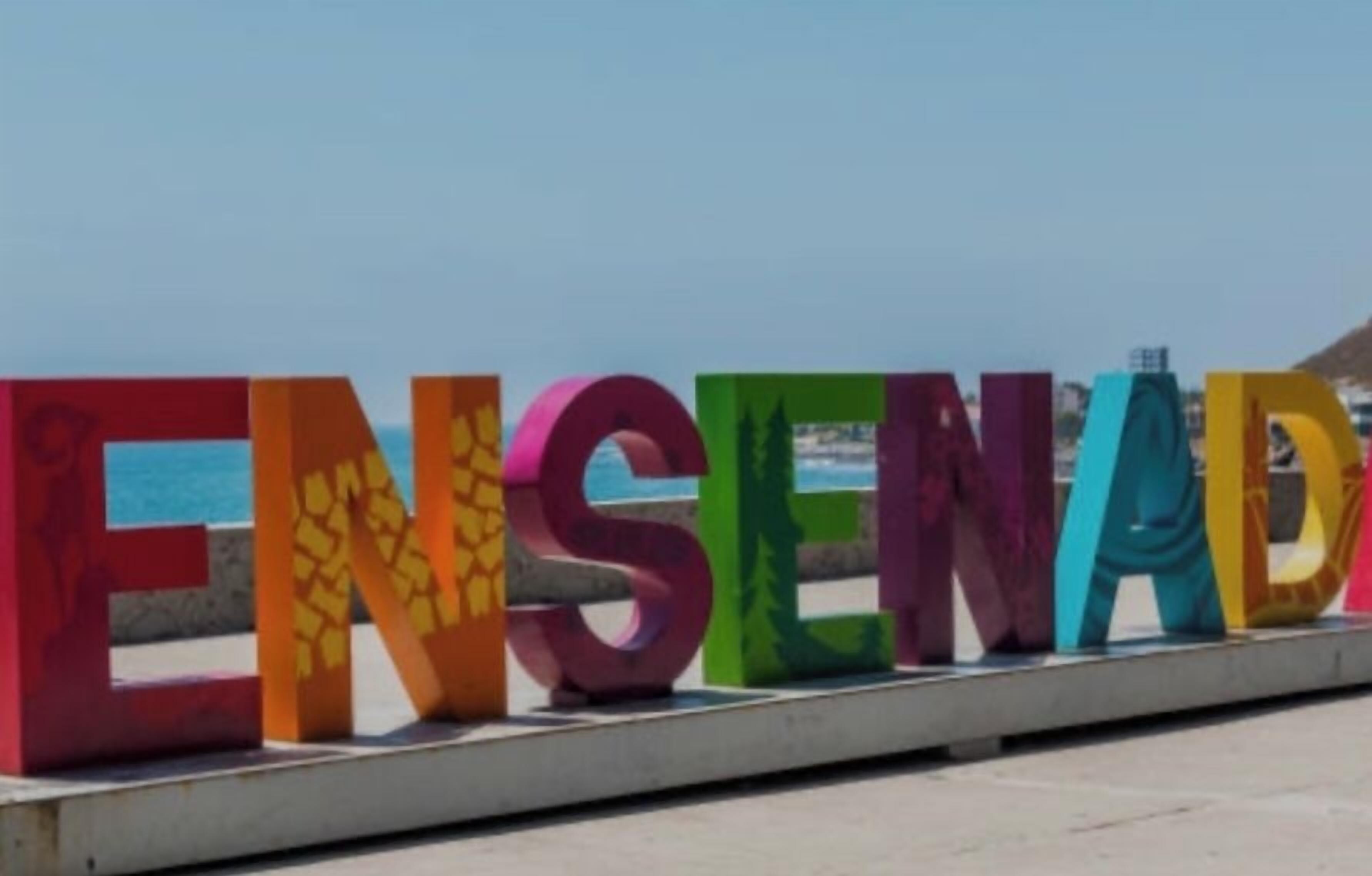 Colorful letters spelling "ENSEÑADA" on a seaside boardwalk.