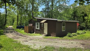 Une petite cabane à un seul étage, avec une porte d’entrée, une fenêtre et un petit porche.