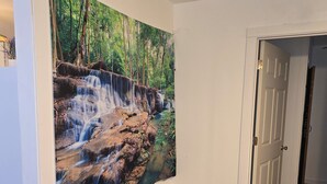 Une pièce avec un grand mur décoré d’une fresque représentant une cascade, un revêtement de sol en moquette et une porte fermée.