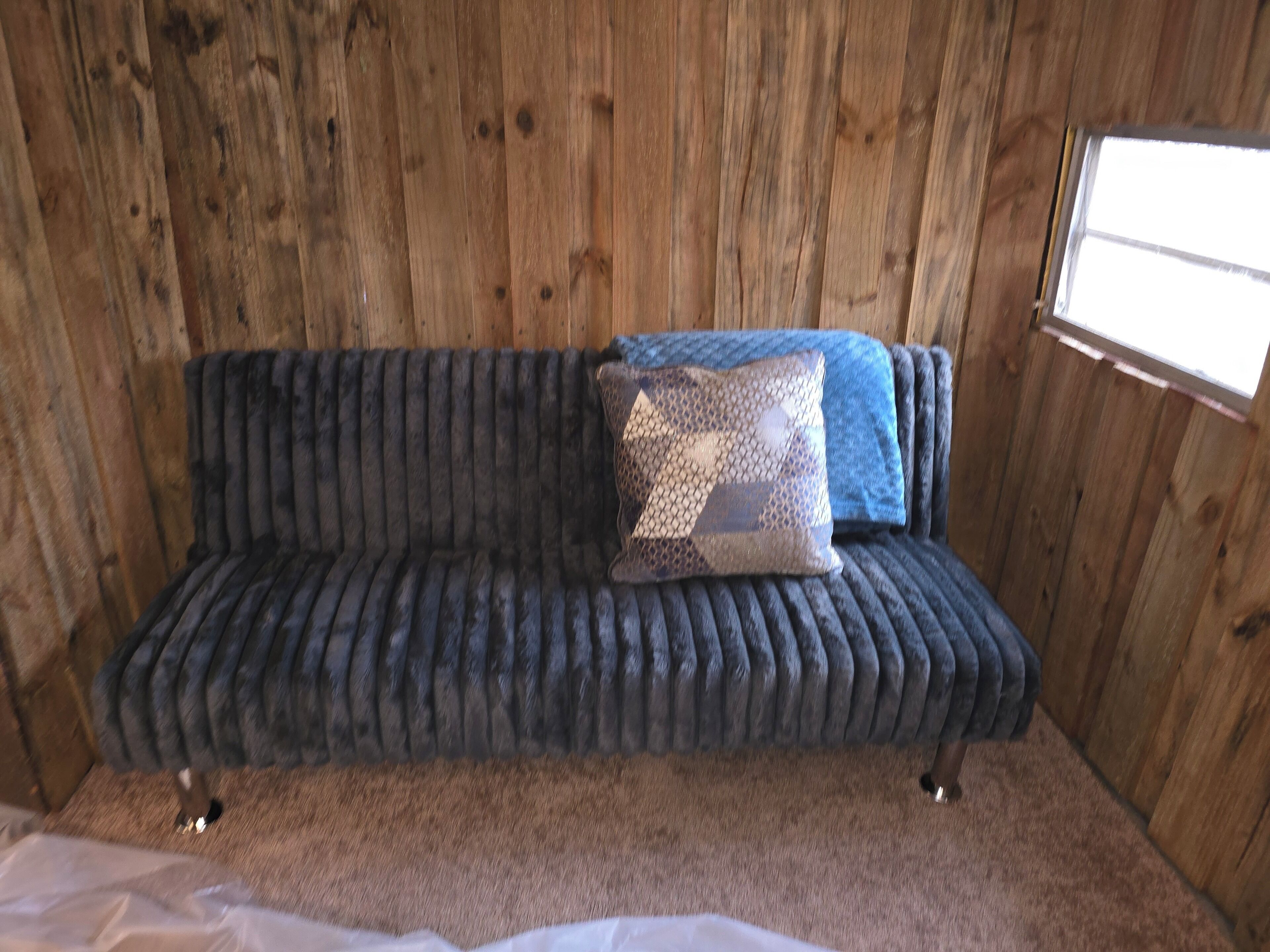 A wooden interior with a dark blue sofa and patterned pillows.
