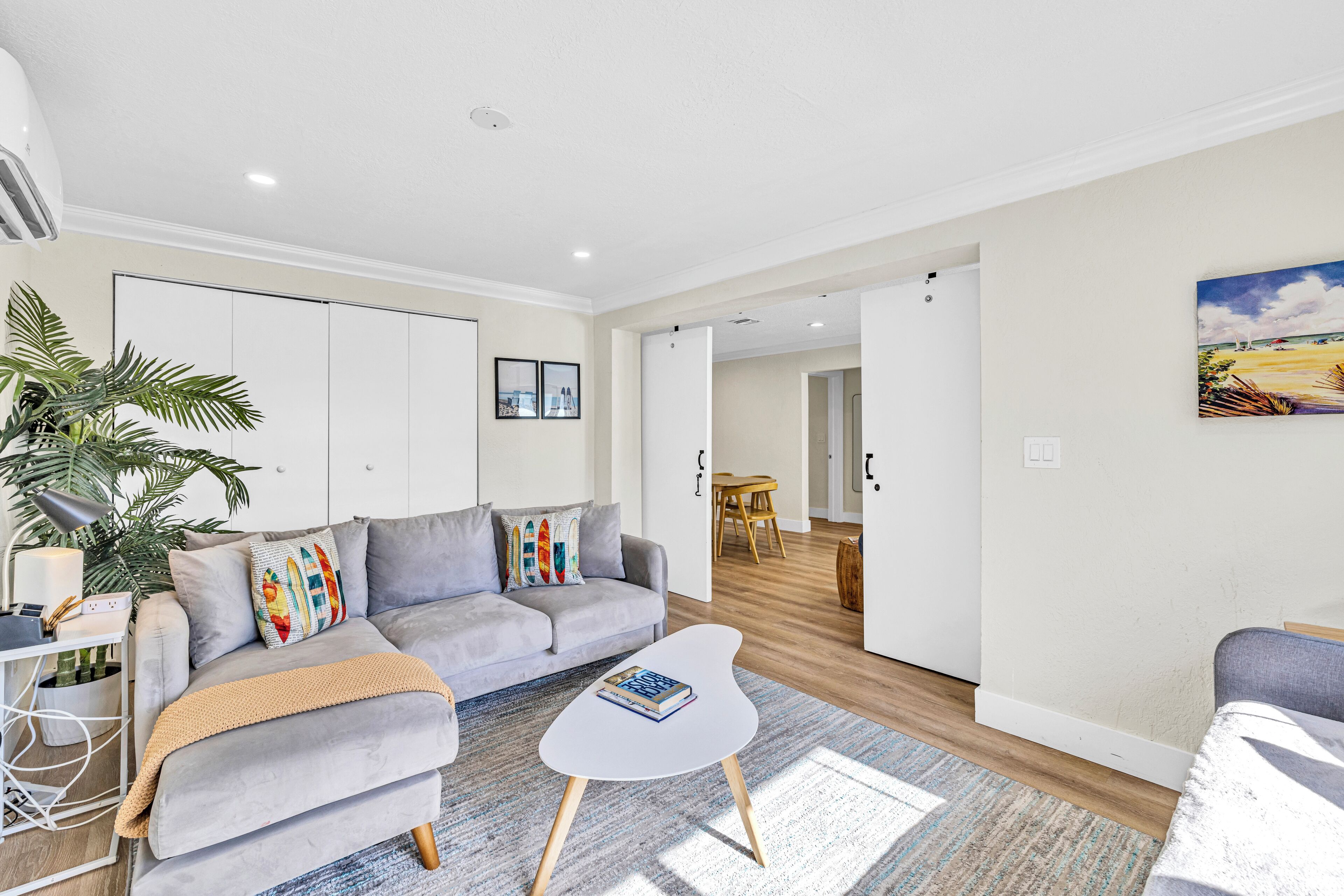 A modern living room with a grey sofa, a white coffee table, and a large plant.