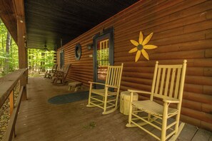 Una cabaña de madera con un porche, mecedoras y una gran decoración floral en la pared.