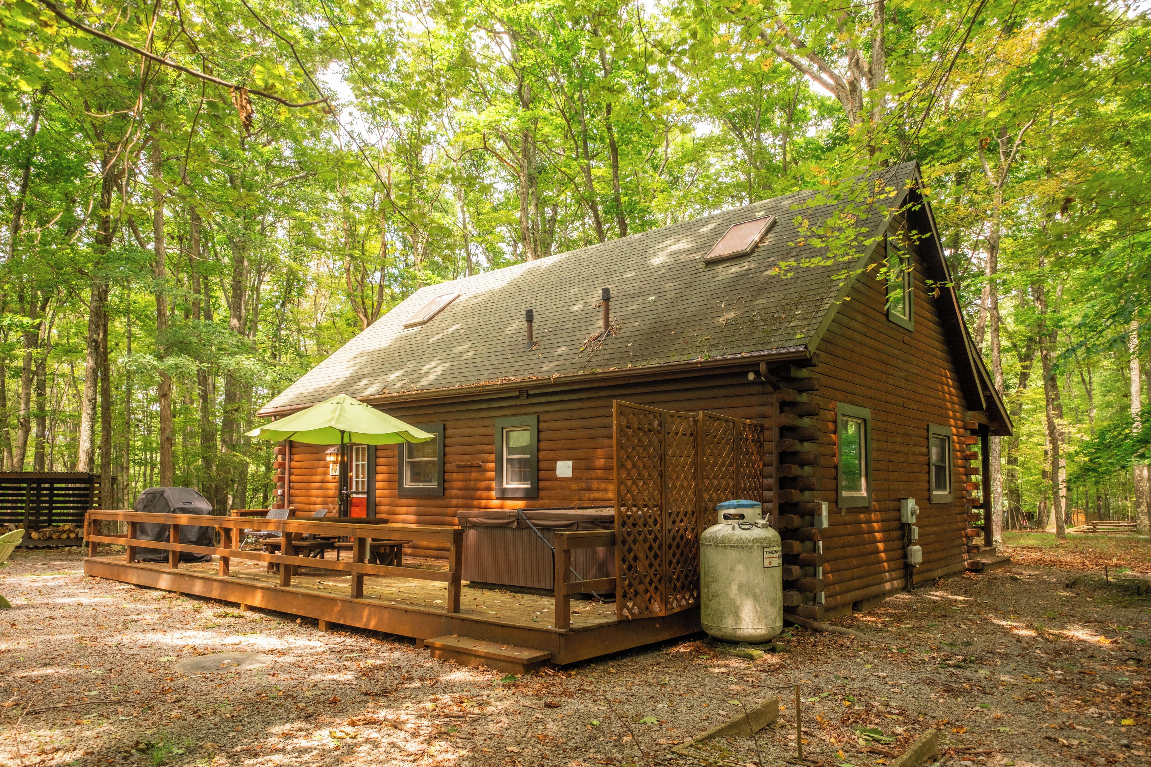 A log cabin with a deck, outdoor seating, and a propane tank.