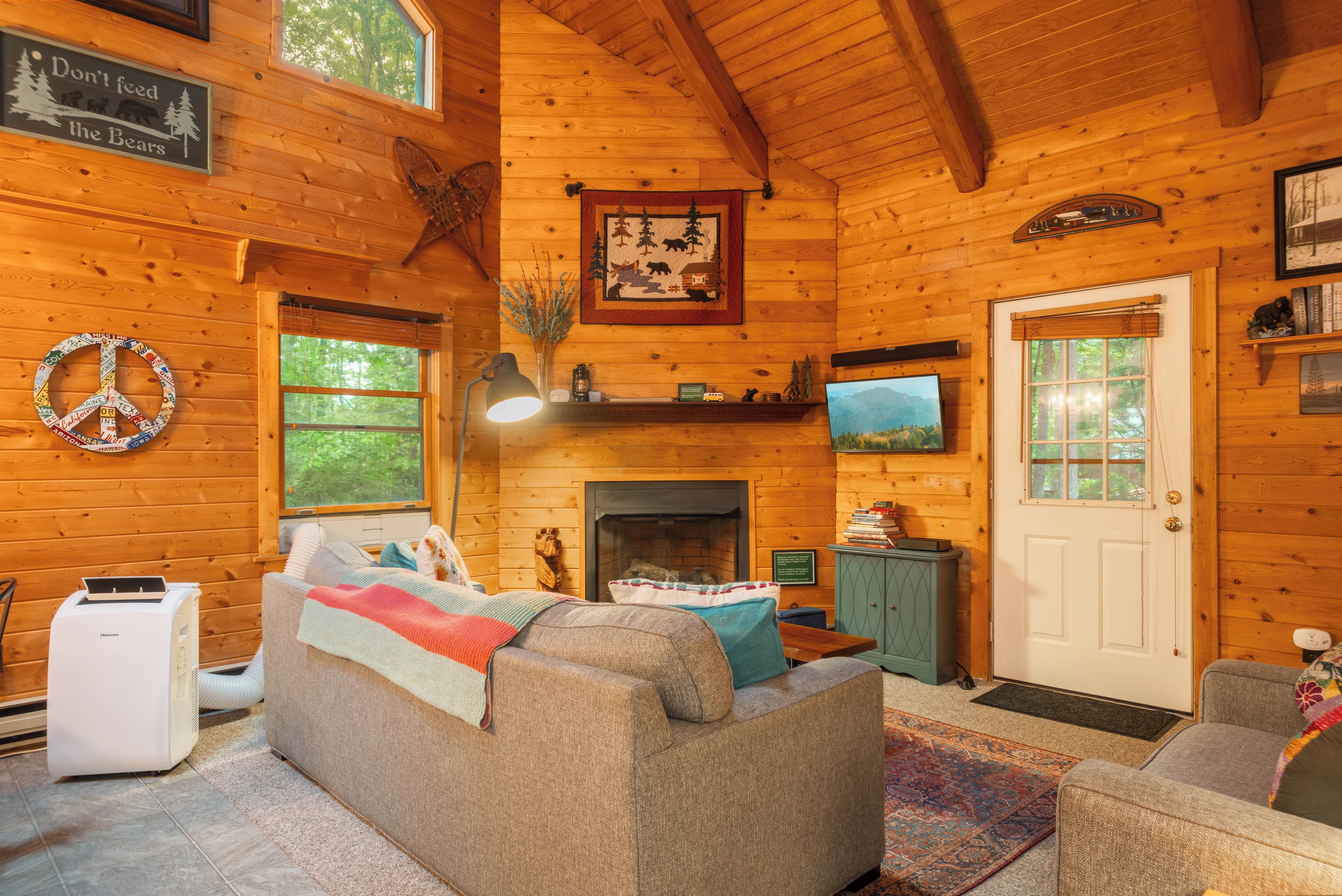 A cozy log cabin interior with a fireplace, a television, and a couch.