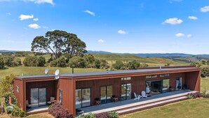 Et moderne hus med stor terrasse, parabolantenner og udsigt over bølgende bakker.