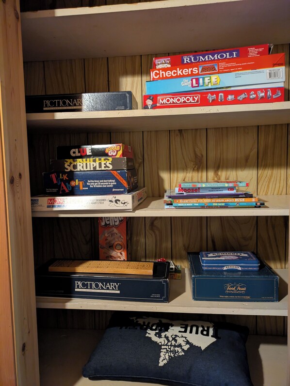 A shelf with various board games, including Pictionary, Monopoly, and Scruples. - Charming Lakeview cabin in a peaceful bay (Saint Laurent)