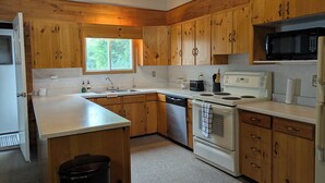 Una cocina con gabinetes de madera, un microondas, una estufa y un lavamanos.