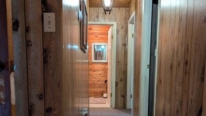 Un pasillo interior de madera con piso alfombrado, una lámpara y una puerta que da a otra habitación.