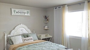Une chambre à coucher comprenant un lit, une table de chevet, une commode, une fenêtre avec des rideaux et un luminaire au plafond.