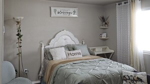 Une chambre à coucher comprenant un lit, une chaise, une table de chevet et un luminaire fixé au mur.
