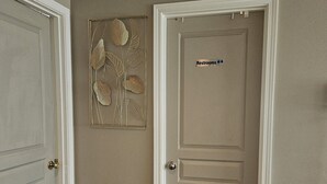 Un couloir avec deux portes, dont une porte sur laquelle est inscrit « Toilettes » et un paillasson sur lequel est écrit « Bienvenue ».