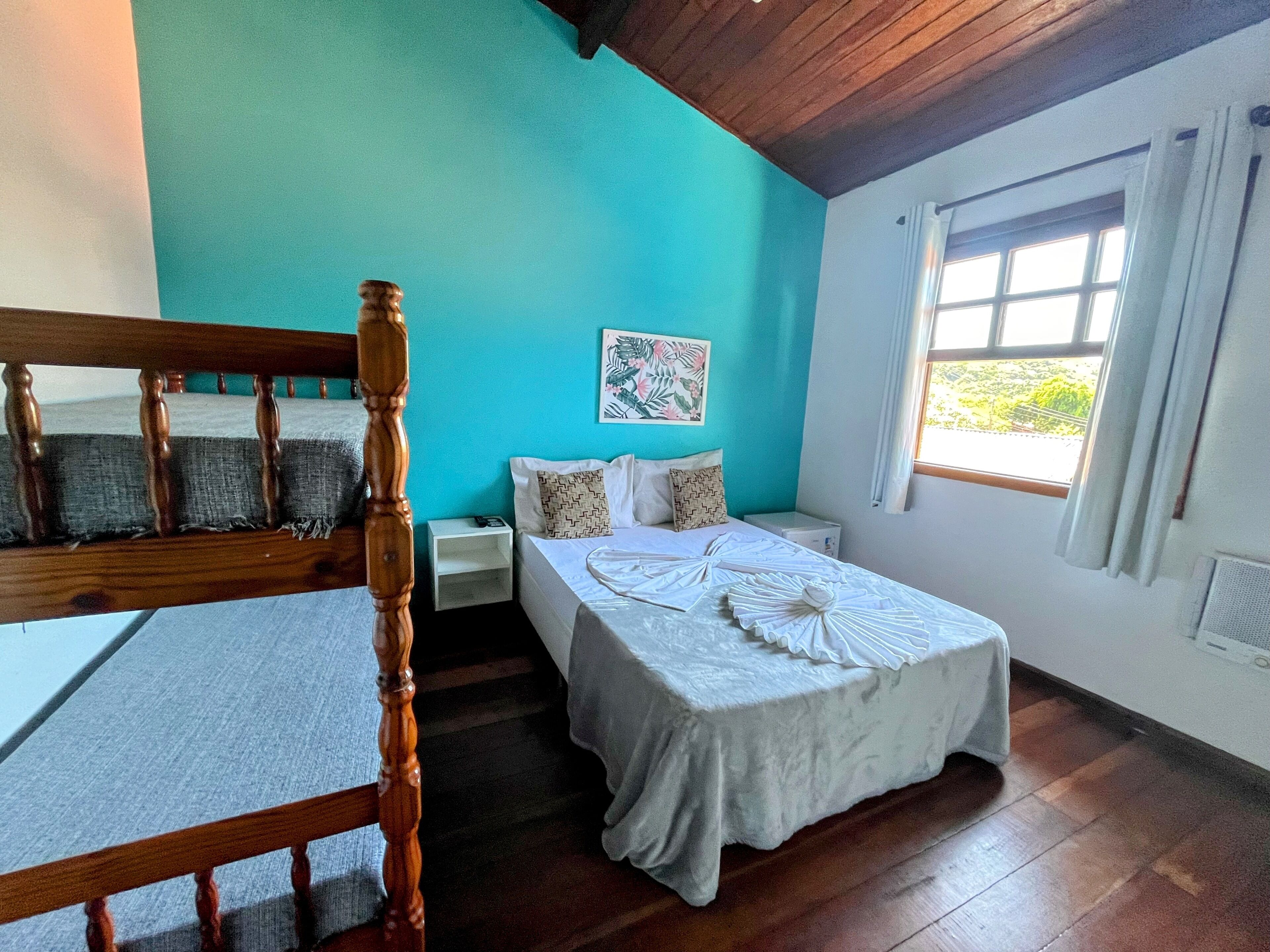 A bedroom with a wooden bed frame, a white bedspread, and a nightstand with a lamp.