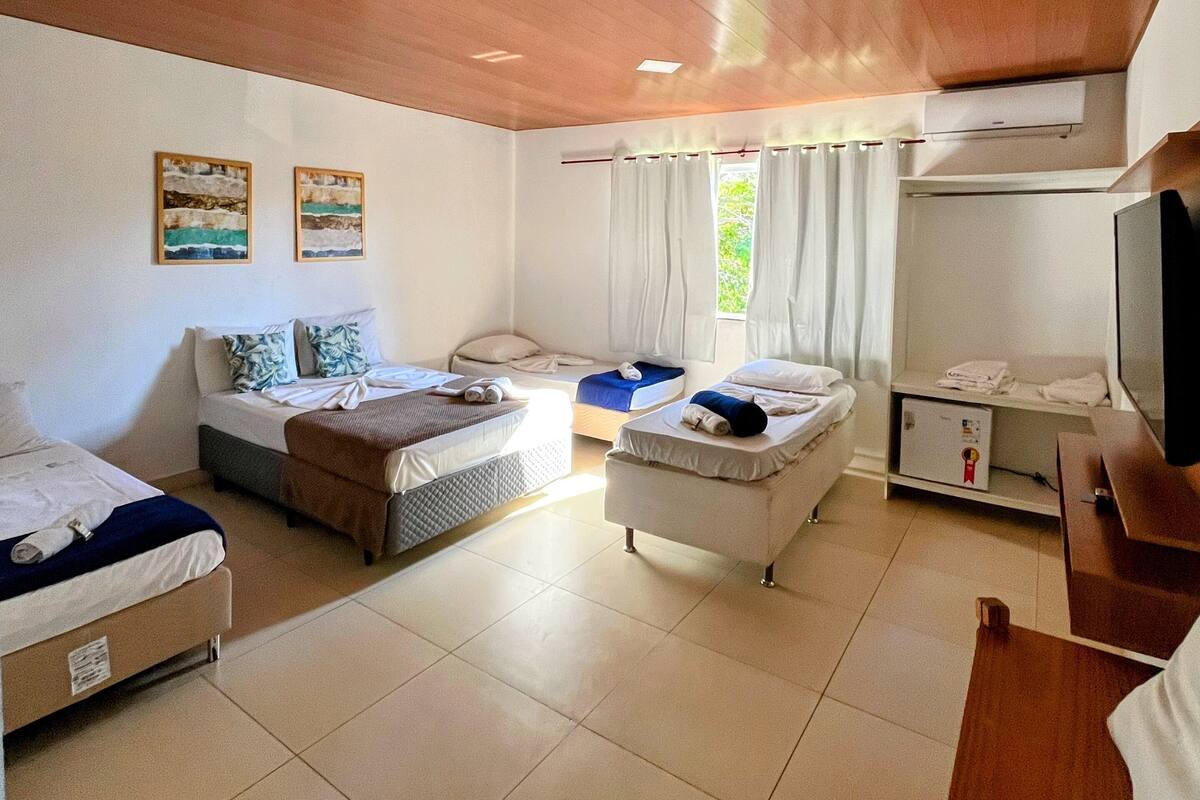 Una habitación de hotel con dos camas, un sofá, un televisor y un equipo de aire acondicionado.
