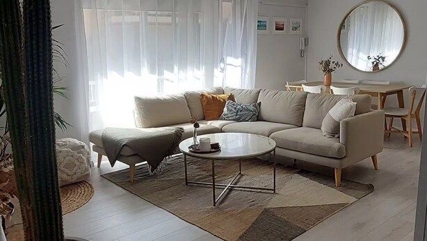 Una sala de estar moderna con ventilador de techo, un sofá, una mesa de centro y un comedor con una mesa redonda y sillas.