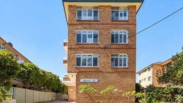 A multi-story residential building with a brick facade, numbered 'Hillcrest 25,' and a gated entrance.