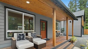 A covered outdoor seating area with wicker furniture and a wooden deck.