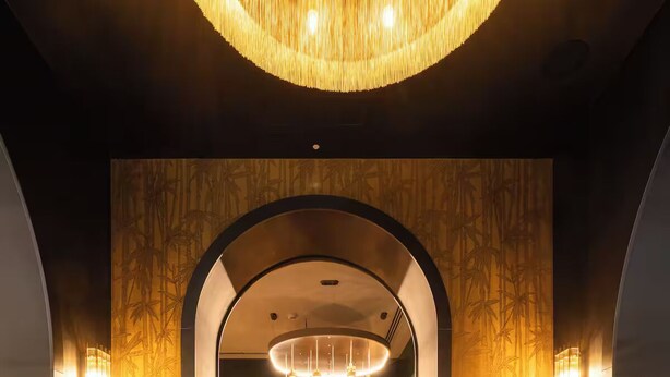 A dimly lit lounge area with a central seating arrangement, a large chandelier, and wall-mounted lighting. - aileenhotel (seoul)