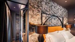 A modern hotel room with a large bed, a headboard with a mirror, and a wall with a detailed mural. - aileenhotel (seoul)