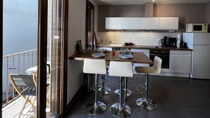A modern kitchen with a dining area, large windows, and a view of the outdoors.